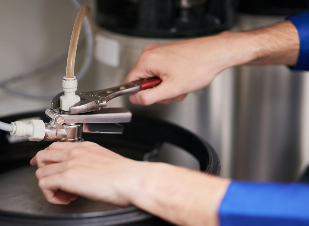 Cropped shot of a handyman repairing a pipe on a water heater  734 884 8885  infolivoniahvac com
